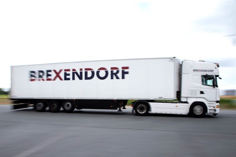 Weißer Sattelschlepper in Bewegung mit "BREXENDORF" auf der Aufliegerseite.